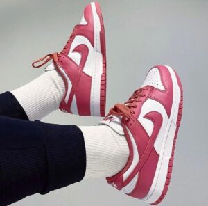 5563a092-98f2-4958-b9ba-bf82d6262cea | UAE SPORT STORE Pink and white sneakers with white socks, laid sideways against a plain background, showcasing the side and bottom of the shoes for product detail.