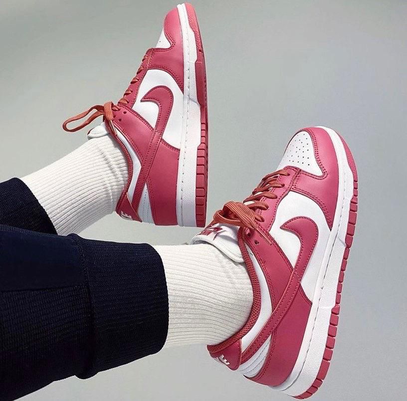 5563a092-98f2-4958-b9ba-bf82d6262cea | UAE SPORT STORE Pink and white sneakers with white socks, laid sideways against a plain background, showcasing the side and bottom of the shoes for product detail.