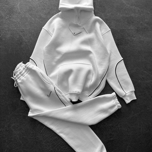 White Nike hoodie and matching joggers laid flat on a dark textured surface, small Nike swoosh on chest and on pants' leg seams.