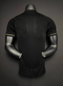 Back view of a black short-sleeve athletic shirt on a mannequin, showing subtle tan piping near the sleeve cuffs.