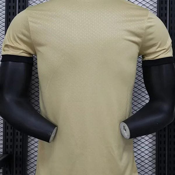 Beige short-sleeve athletic shirt on a black mannequin seen from the back, in a store display against a metal mesh backdrop.