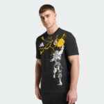 56cc71d0-d779-43e8-915b-f27ddf628217 | UAE SPORT STORE Model wearing a black graphic T-shirt with yellow crackle design and a white illustrated figure, standing against a light background.