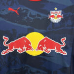 Red Bull logo with two charging red bulls around a yellow circle on a dark blue shirt; Red Bull Salzburg crest above.