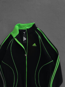 Black Adidas sports jacket with bright neon green piping and zippers, logo visible on chest area