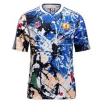 Blue, black, and peach paint-splatter soccer jersey featuring an Adidas logo and Manchester United crest on the chest area (front view).
