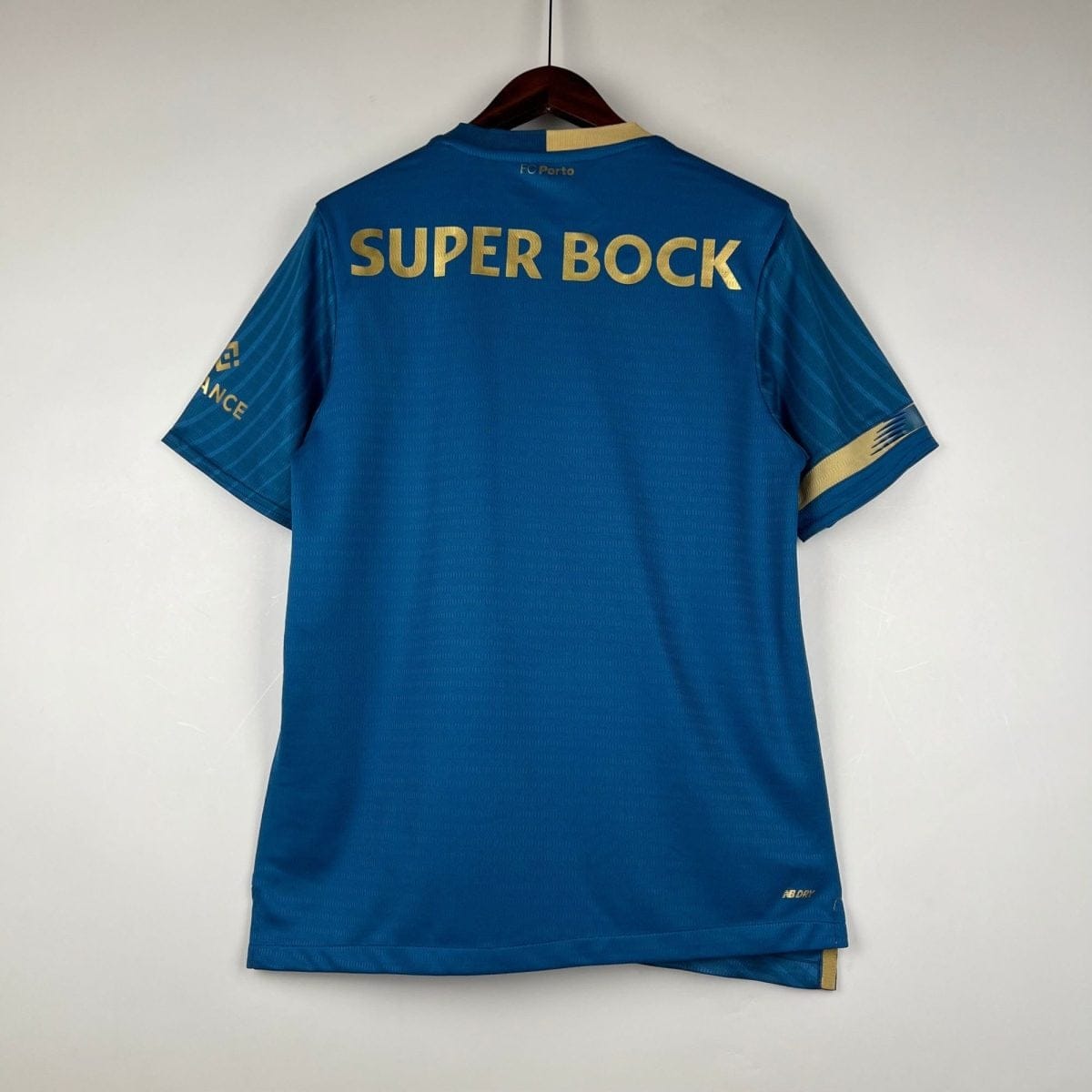Blue football jersey hanging on a wooden hanger, gold 'SUPER BOCK' across the back and 'FC Porto' near the neck.