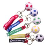 Five soccer ball keychains with colored straps (red, blue, green, yellow, black) and a small ball at the end, each reading 'FIFA WORLD CUP' on the strap, arranged in a fan.