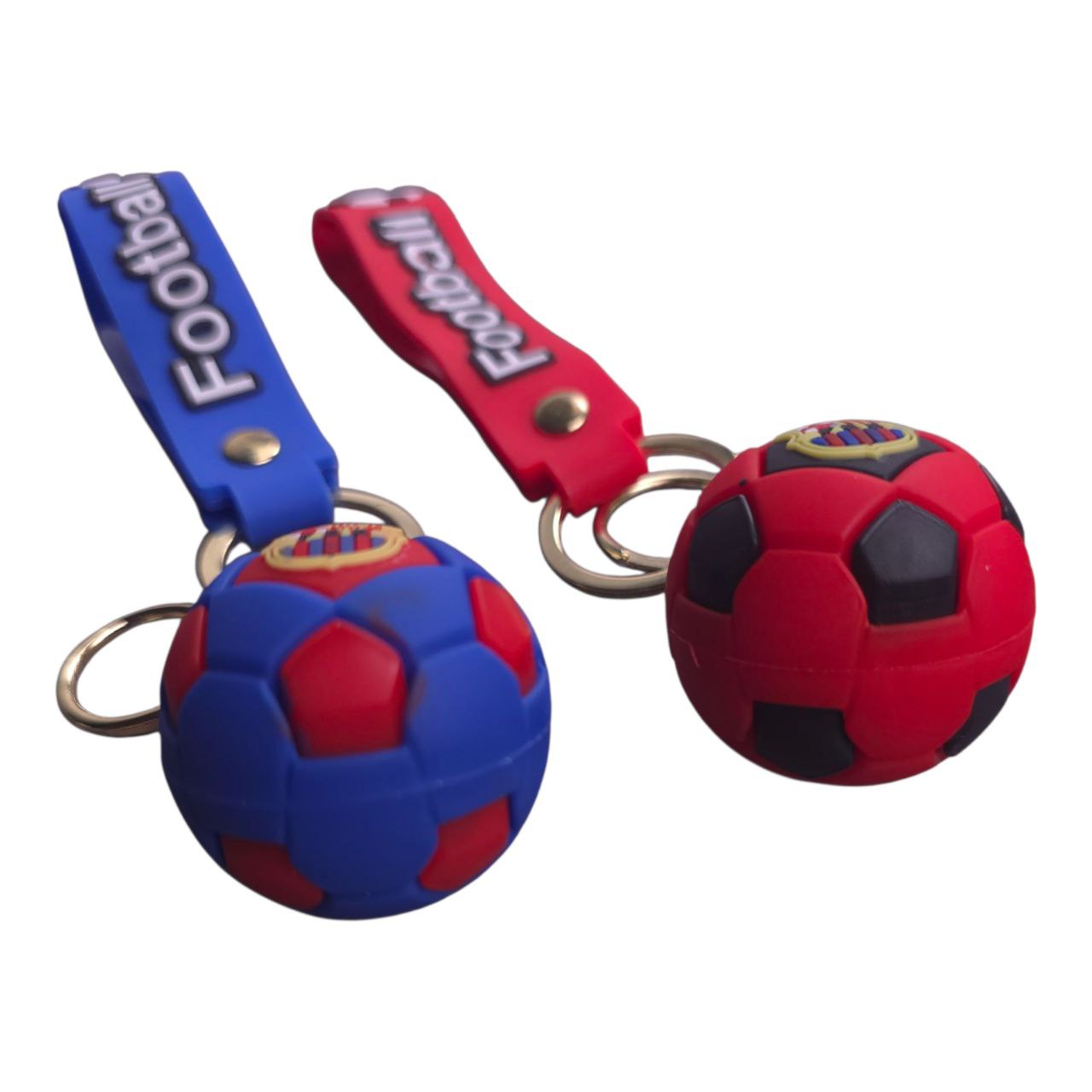 5805548633519671588 | UAE SPORT STORE Two small soccer ball keychains, blue and red, with matching straps attached to metal key rings.