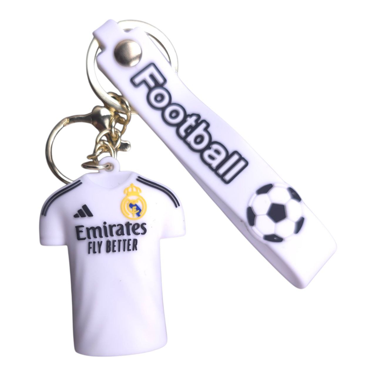5805548633519671630 | UAE SPORT STORE White keychain set featuring a Real Madrid jersey charm and a small soccer ball charm, with Emirates Fly Better branding on the jersey and strap.
