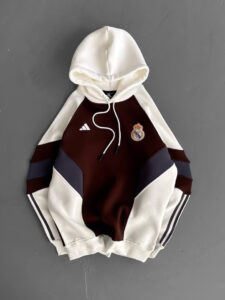 Real Madrid Adidas hoodie with white sleeves and hood, burgundy chest with navy panels, crest on the left chest, white drawstrings.
