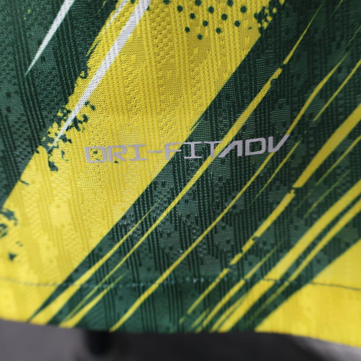 Close-up of yellow and green diagonal striped safety tape with a textured fabric surface.