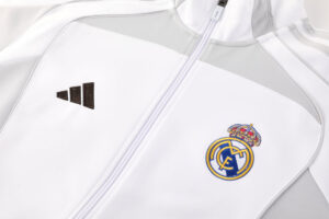 White athletic jacket with a zipper, featuring the Real Madrid crest on the left chest and the Adidas logo on the right.