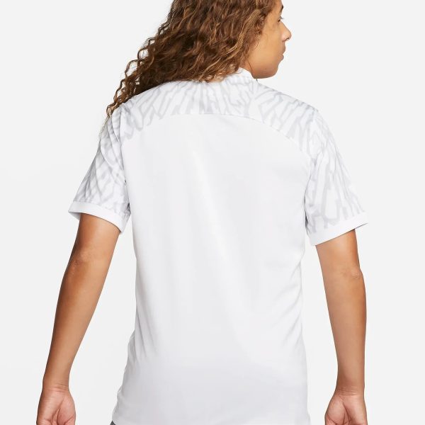 Back view of a person wearing a white shirt with light gray patterned shoulders and gray cargo shorts visible at the bottom/