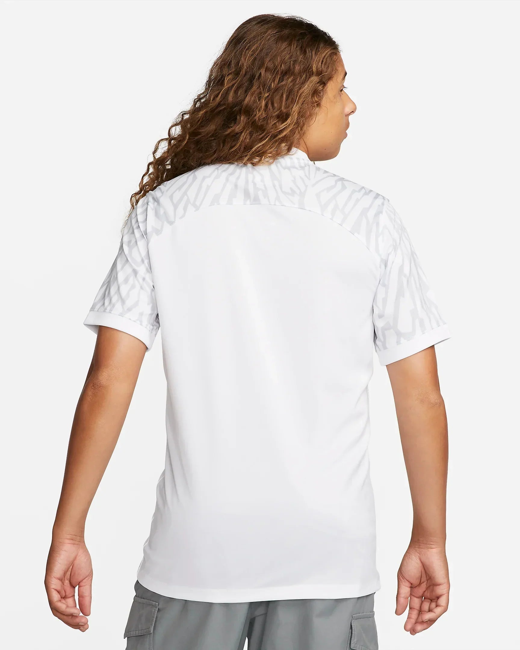 58e2989f-ced4-4bf3-a9fa-9b378585efe0_4be1ed7e-d40e-4663-80c2-dde700a4436a | UAE SPORT STORE Back view of a person wearing a white shirt with light gray patterned shoulders and gray cargo shorts visible at the bottom/