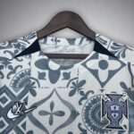 Light gray-blue patterned sports jersey on a hanger, featuring a Nike swoosh and the Portugal crest.