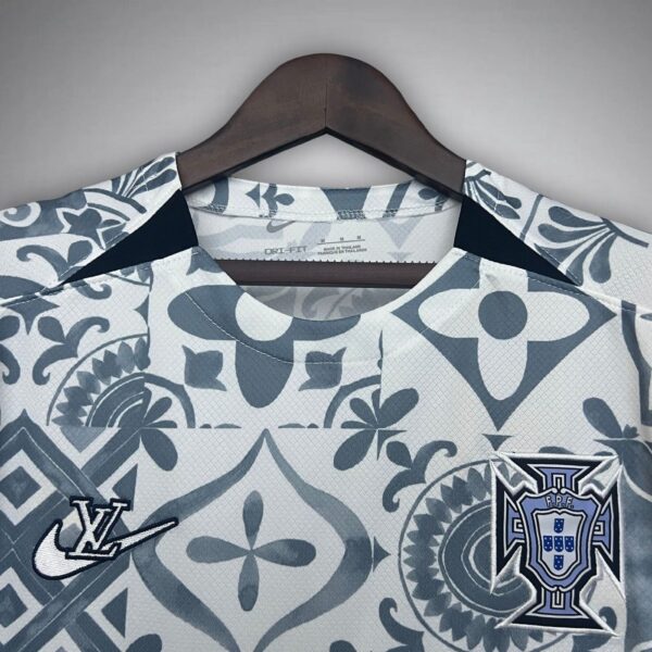 Light gray-blue patterned sports jersey on a hanger, featuring a Nike swoosh and the Portugal crest.