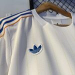 592863432_1158609286421625_215589034613972149_n | UAE SPORT STORE White Adidas jersey on a hanger with light pinstripes and a blue Trefoil logo on the chest; blue and orange shoulder stripes.A0