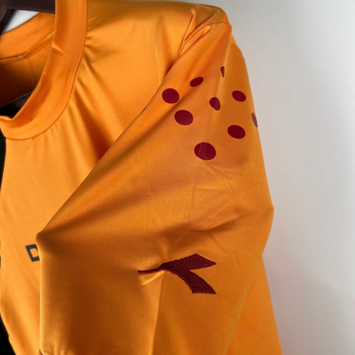 Close-up of orange fabric with maroon polka dots, draped in folds.