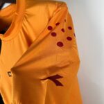 Close-up of orange fabric with maroon polka dots, draped in folds.