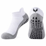 White and gray athletic socks with a grip-patterned sole and a black logo on the heel area, shown from the side and bottom for product detail