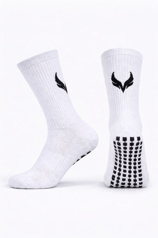 Pair of white athletic socks standing upright, with black logo near the top and dotted grip pattern on the sole.