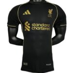 Black Liverpool FC soccer jersey in black with gold Adidas logo, Gold crest, and gold 'Standard Chartered' sponsor on the front, displayed on a mannequin torso.