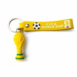 Yellow FIFA World Cup keychain with a small replica trophy and a soccer ball emblem on the strap.