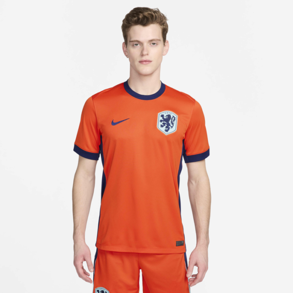 Male model wearing an orange soccer jersey with navy trim and team crest on the chest, product shot