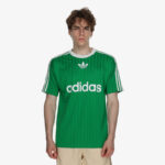 Male model wearing a green Adidas jersey with white stripes and trefoil logo, front view.