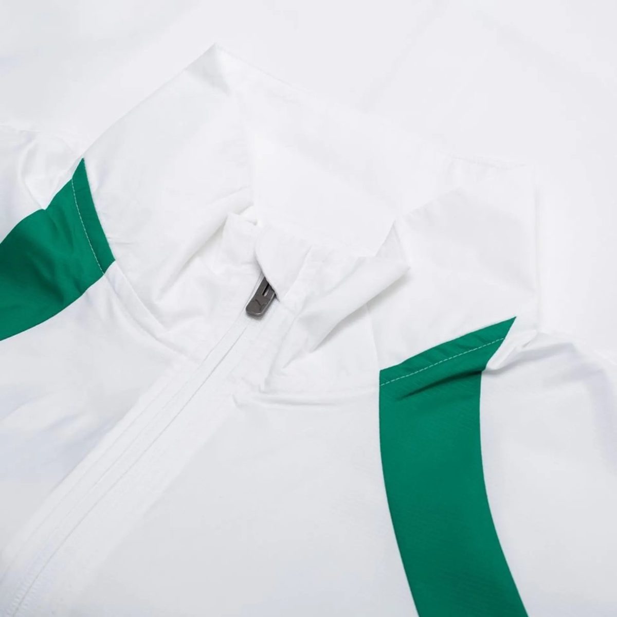 Close-up of white fabric with a green diagonal stripe and a zipper, suggesting a bag or garment detail.