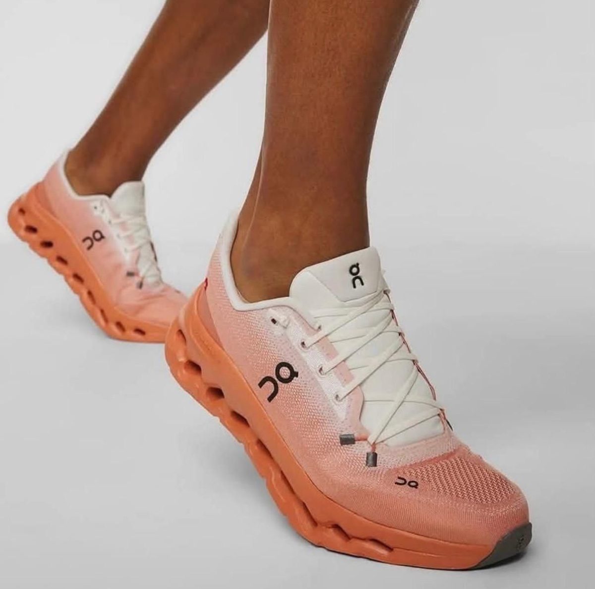 Peach-pink On running shoe with white laces on a wearer’s foot, showcasing a chunky sole.