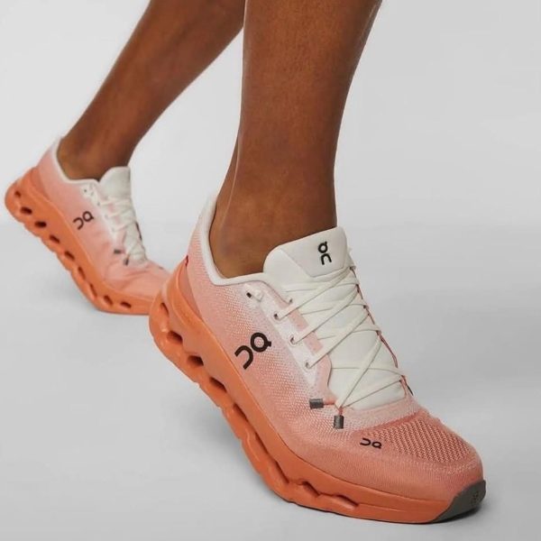 Peach-pink On running shoe with white laces on a wearer’s foot, showcasing a chunky sole.