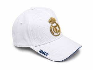 White baseball cap with Real Madrid crest in gold on the front and RMCF lettering on the brim edge.