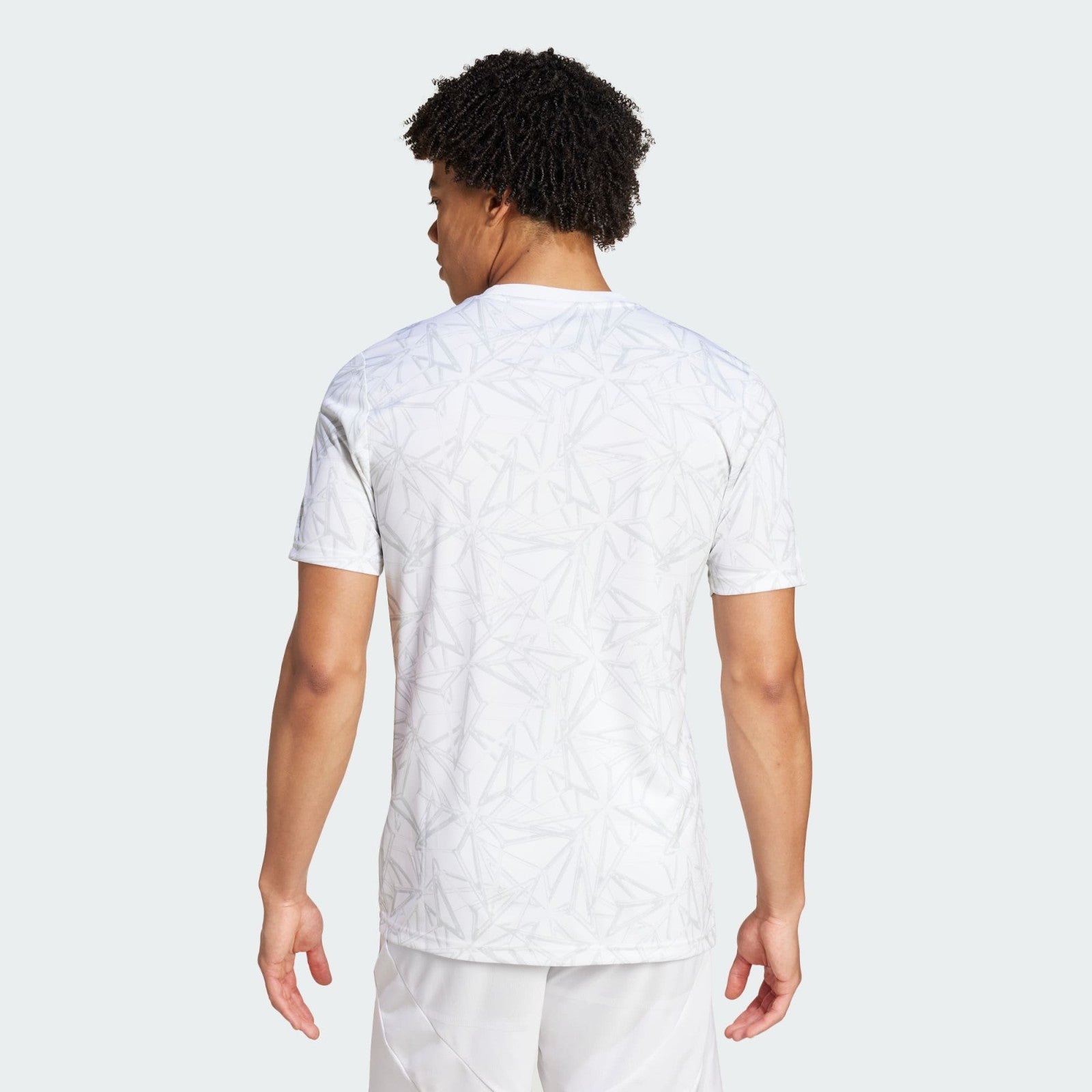 5TTue4M2GXLoxpv | UAE SPORT STORE Back view of a person wearing a white T-shirt with a pale gray geometric pattern, against a light gray background.