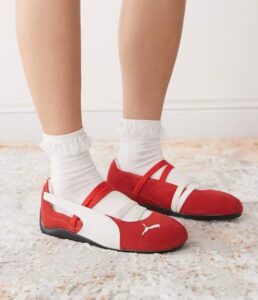 5a1f9b37-3d1b-4aa8-8715-d94d27a285ce | UAE SPORT STORE Red and white Puma sneakers with white socks on a light rug, shown from the side.