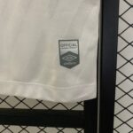 Close-up of light gray fabric with an official licensed product badge and Umbro logo near a black frame.