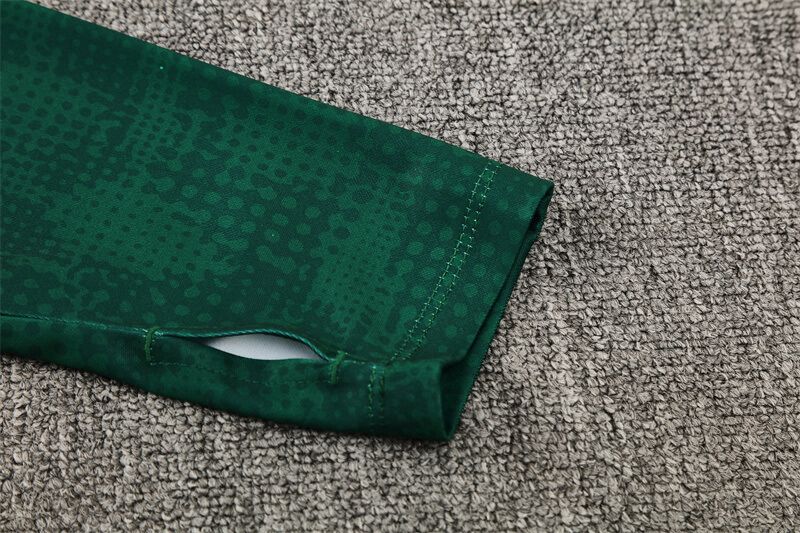 5b06e26a-8d23-4f83-986a-266024f9ab56 | UAE SPORT STORE Close-up of a dark green athletic sleeve with a thumbhole lying on a gray carpet.