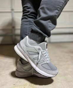 5b14f883-f148-4a11-91dd-d4689d52a419_13cabed3-565a-4785-8854-40cf60599029 | UAE SPORT STORE Gray athletic sneaker with a white sole, worn with dark joggers, shown in a toe-up pose on concrete outdoor flooring.