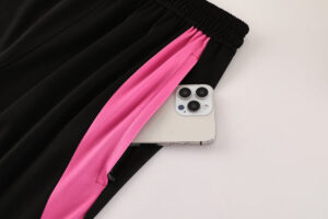 Black pants with a pink side stripe, showing a phone partially tucked into a zippered pocket.