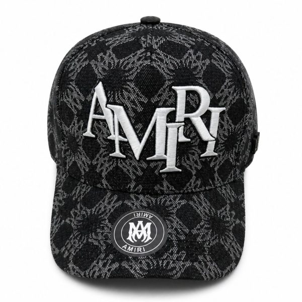 Black patterned baseball cap with large white AMIRI embroidery on the front panel and a circular AMIRI patch on the brim area, fashion accessory.