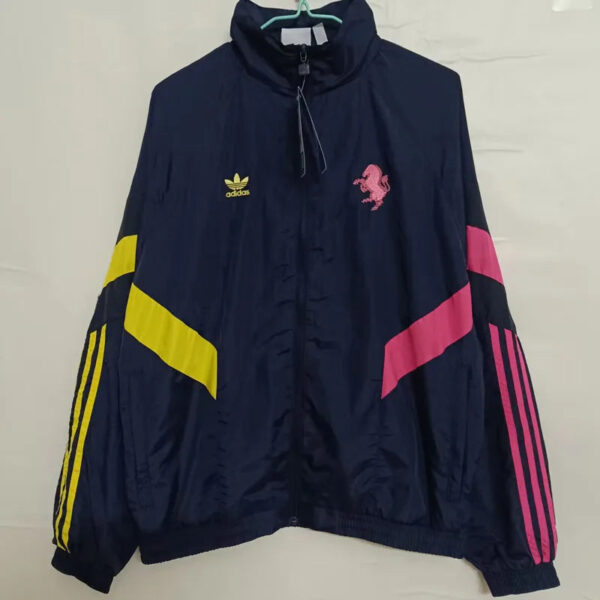 Navy windbreaker with Adidas logo on left chest and pink flamingo emblem on right; yellow diagonal stripe on left sleeve and pink accents on right sleeve.