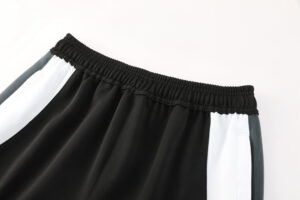 Close-up of the black elastic waistband on color-block athletic shorts with white and gray side panels.