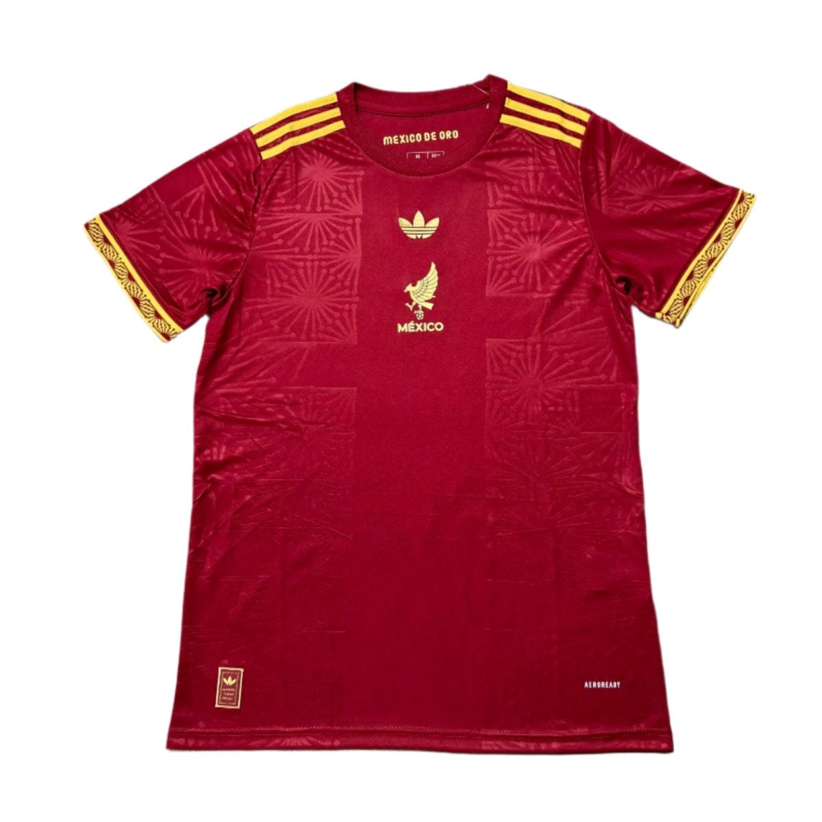 Red Adidas Mexico football jersey with gold crest and stripes, decorative gold pattern on sleeves and chest, and Aeroready marking near the hem.