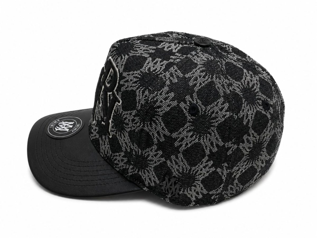 Black lace-patterned baseball cap with a curved brim and a circular logo patch on the brim.