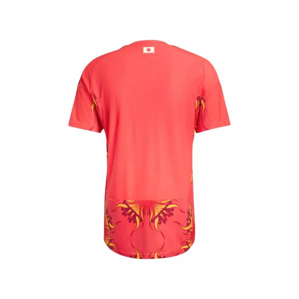 Back view of a red athletic jersey with yellow flame-like patterns along the hem and a small flag label at the upper back