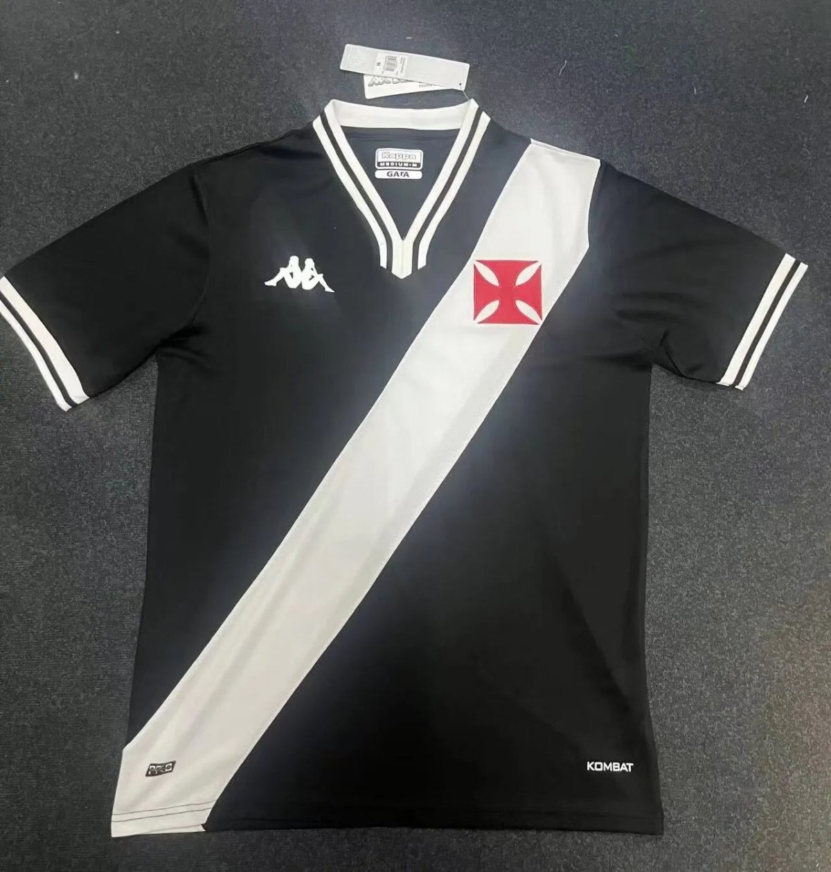 Black soccer jersey with a diagonal light grey sash from shoulder to hip, Kappa logos, and a red Maltese cross crest on the chest.