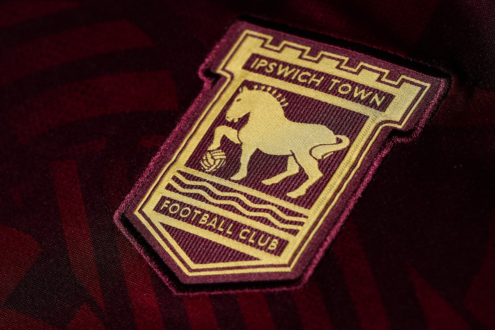 5er40xZ3ZpPsMZl | UAE SPORT STORE Ipswich Town Football Club crest embroidered on a maroon fabric, featuring a golden horse and waves.