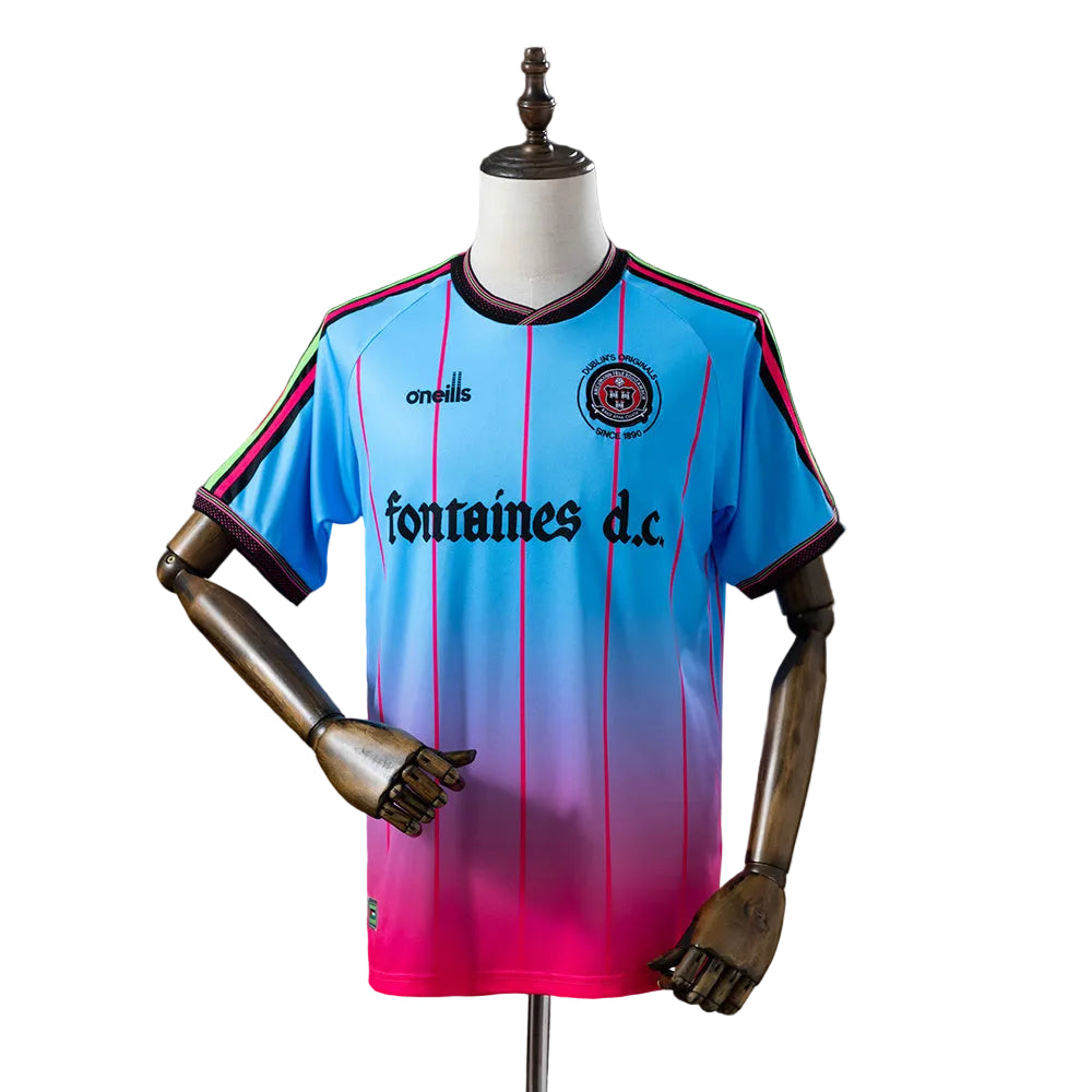 5f393dc7 | UAE SPORT STORE Blue to pink gradient soccer jersey with vertical pink stripes on a mannequin, featuring 'fontaines d.c.' sponsor text and club crest on the chest.