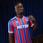 Smiling man wearing a blue and red striped football jersey with the NET88 sponsor logo.
