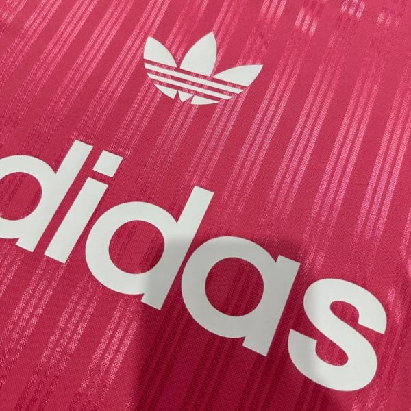 Close-up of a bright pink Adidas jersey featuring the white trefoil logo and part of the bold white adidas text.